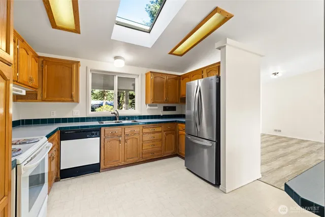 a kitchen with stainless steel appliances granite countertop a refrigerator a stove a sink and a microwave