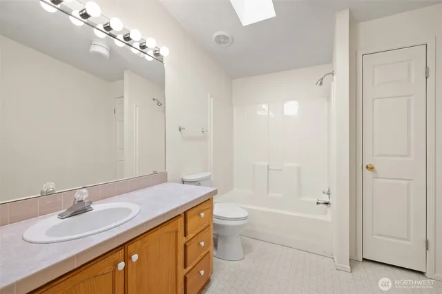 a bathroom with a granite countertop sink a toilet and shower