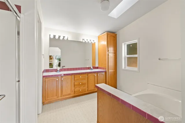 a bathroom with a tub a sink and a large mirror