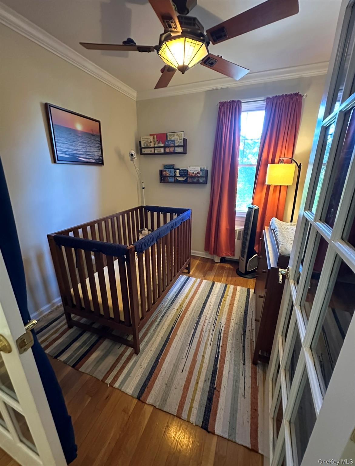 100 Cedar Street, Unit A21 Dobbs Ferry, NY 10522 - Photo 9 of 12 Bedroom featuring wood finished floors, a crib, crown molding, and a ceiling fan