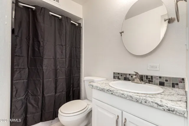 a bathroom with a granite countertop sink toilet and a mirror