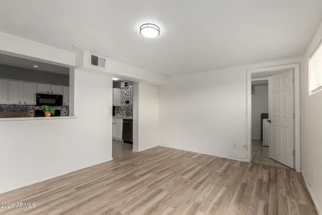 a view of a big room with wooden floor and a kitchen