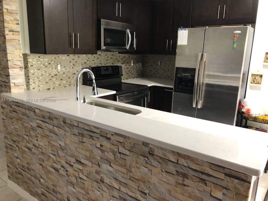14012 Southwest 179th Street Miami, FL 33177 - Photo 4 of 17 a kitchen with stainless steel appliances wooden cabinets a sink and a microwave