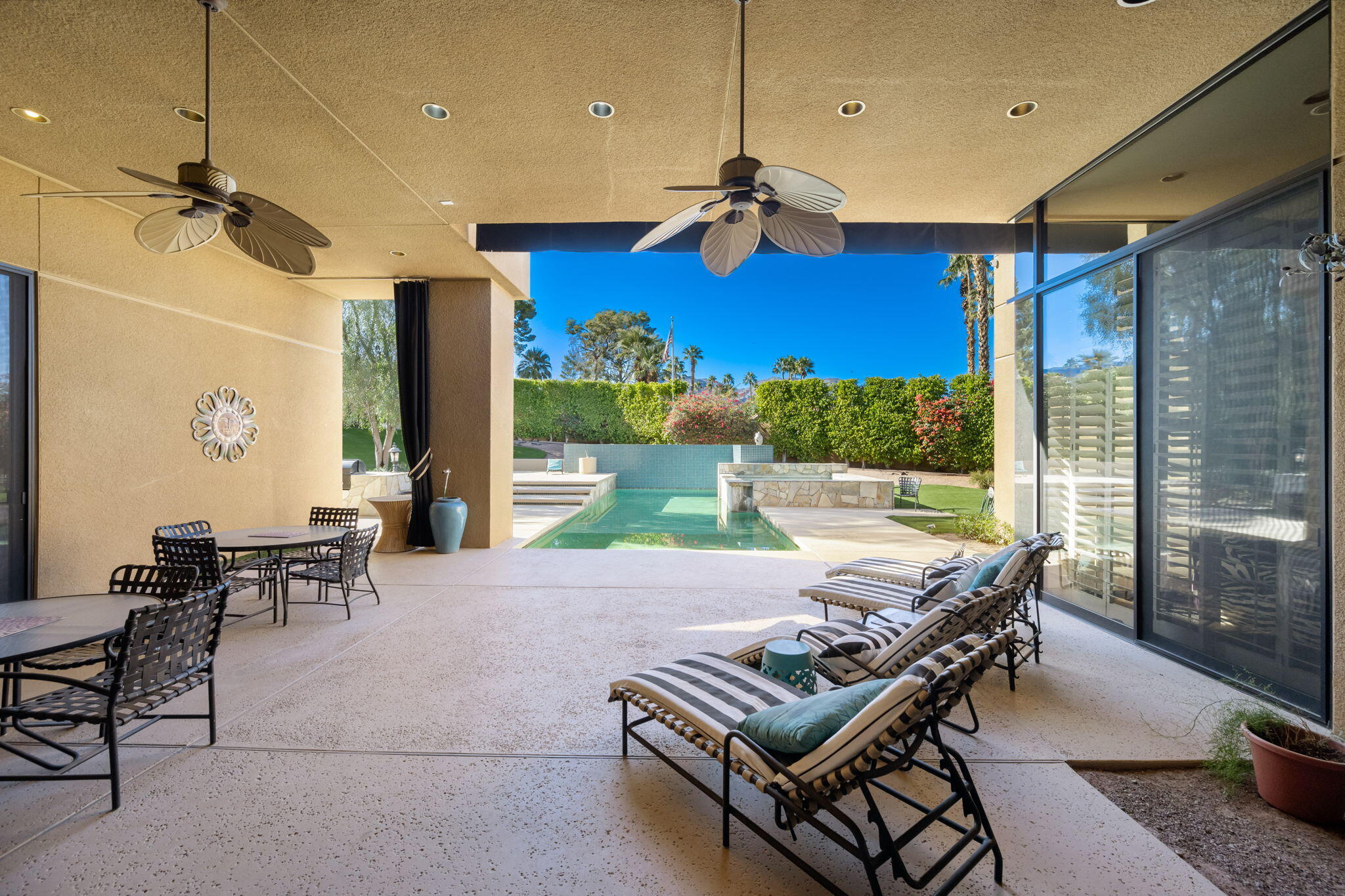 73380 Agave Lane Palm Desert, CA 92260 - Photo 46 of 81 a view of a patio with a dining table chairs and a floor to ceiling window