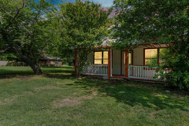a view of a house with a yard and a large tree