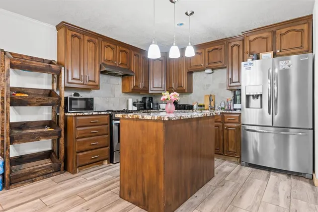 a kitchen with stainless steel appliances granite countertop a refrigerator a oven a sink and dishwasher with wooden floor