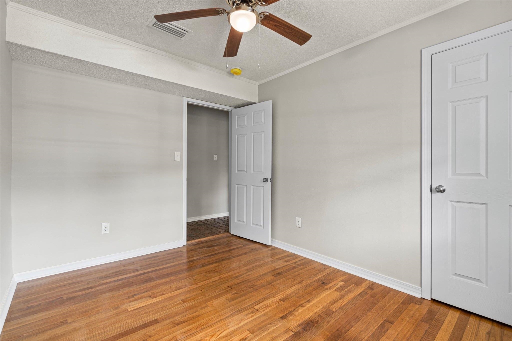 4700 Bit And Spur Road Mobile, AL 36608 - Photo 14 of 21 Unfurnished bedroom with a ceiling fan, crown molding, light wood-style flooring, baseboards, and visible vents