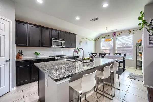 a kitchen with granite countertop kitchen island a table and chairs in it