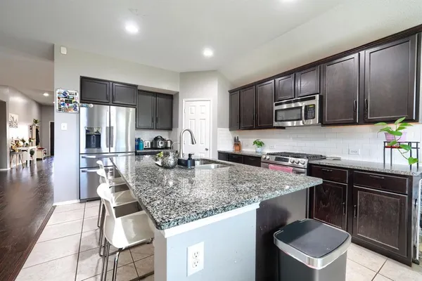 a kitchen with kitchen island granite countertop a sink stove and refrigerator