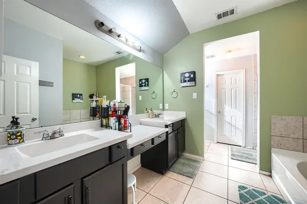 a bathroom with a sink vanity granite tub shower and a mirror