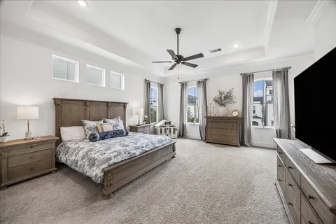 a bedroom with a large bed a flat tv screen and a chandelier