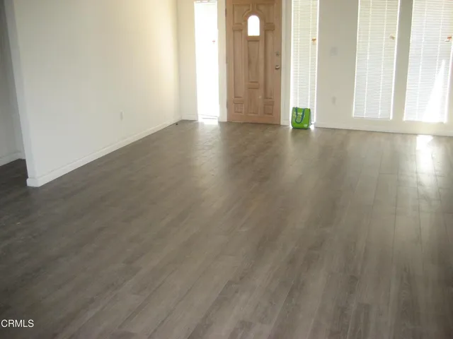 a view of an empty room with wooden floor and windows