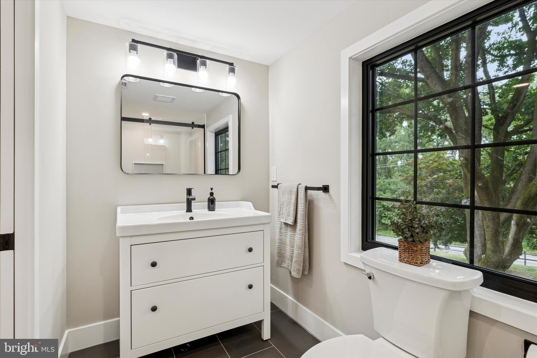 306 Greenhill Road West Chester, PA 19380 - Photo 22 of 42 a bathroom with a toilet a sink a window and mirror