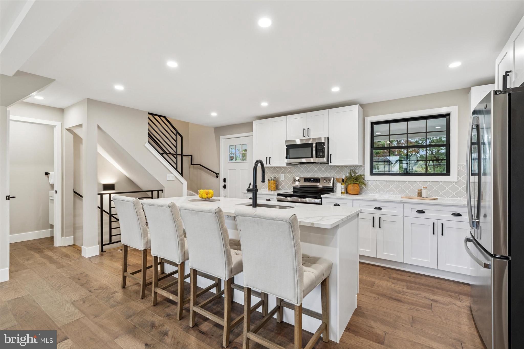 306 Greenhill Road West Chester, PA 19380 - Photo 7 of 42 a kitchen with stainless steel appliances a refrigerator a stove a microwave oven a sink dishwasher and white cabinets with wooden floor