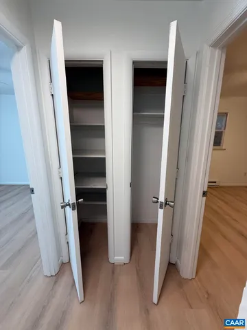 a view of an empty room with a window and wooden floor