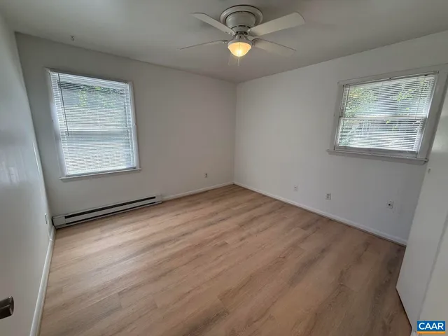 an empty room with wooden floor a ceiling fan and entryway