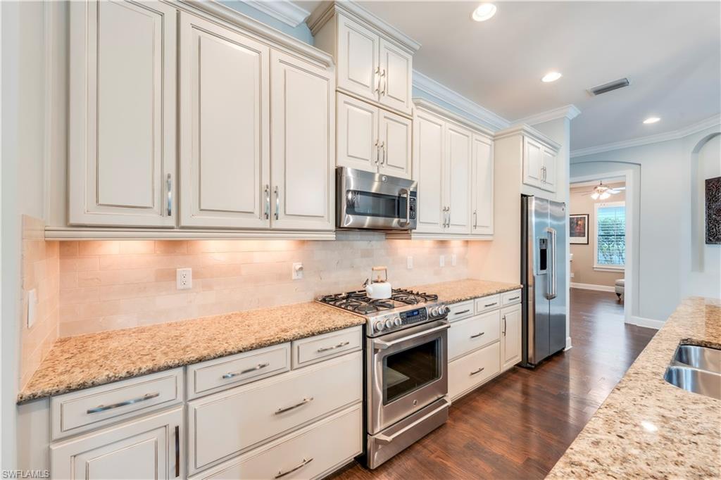 23778 Pebble Pointe Lane Estero, FL 34135 - Photo 7 of 35 a kitchen with granite countertop white cabinets and stainless steel appliances