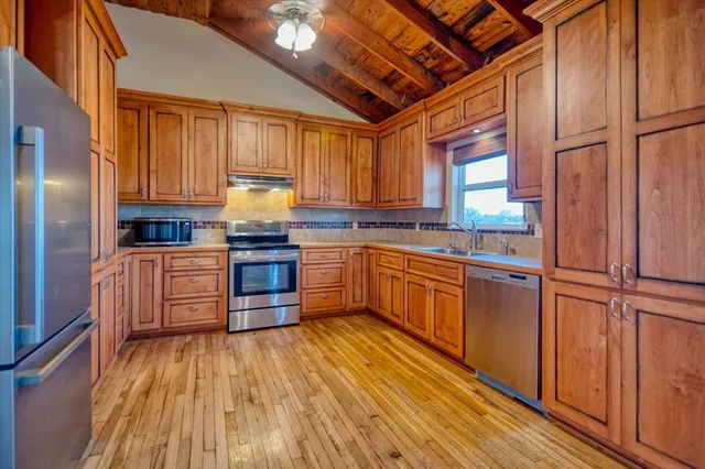 a kitchen with granite countertop wooden floors stainless steel appliances and cabinets