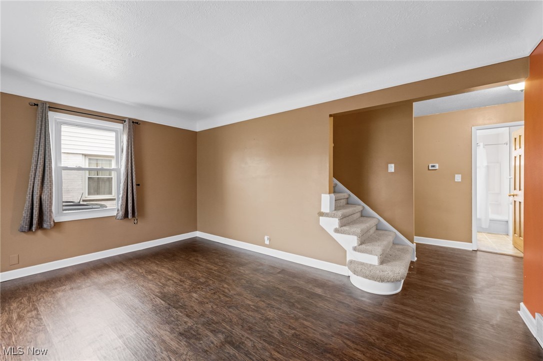 625 Pendley Road Willowick, OH 44095 - Photo 5 of 28 Unfurnished living room featuring dark wood finished floors, stairs, and a textured ceiling