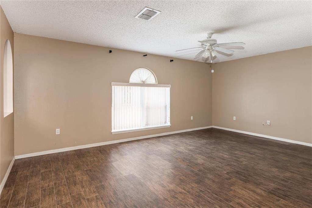 5665 Northwest Whitecap Road Port St. Lucie, FL 34986 - Photo 5 of 25 an empty room with wooden floor fan and windows