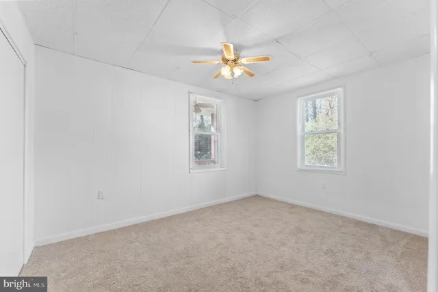 an empty room with a window and a fan