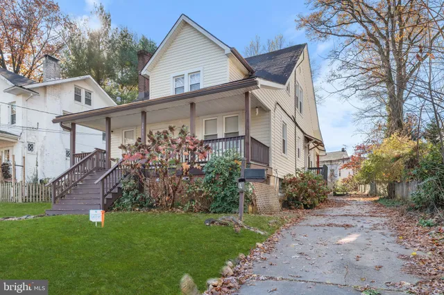 a view of a white house next to a yard with big trees