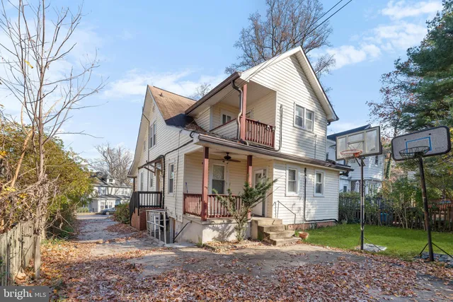 a view of a white house next to a yard with big trees