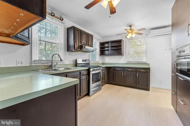 a kitchen with stainless steel appliances granite countertop a sink a stove top oven a refrigerator with island and chairs