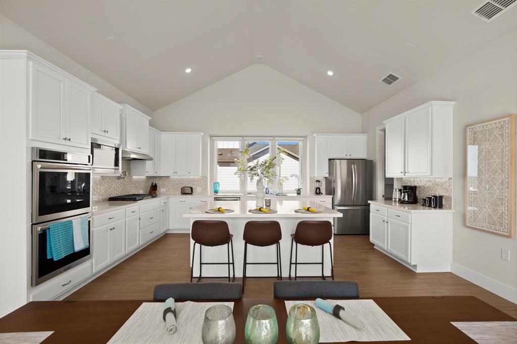 8810 Bestride Bend Austin, TX 78744 - Photo 6 of 35 a kitchen with stainless steel appliances kitchen island granite countertop a stove a sink a refrigerator and white cabinets with wooden floor