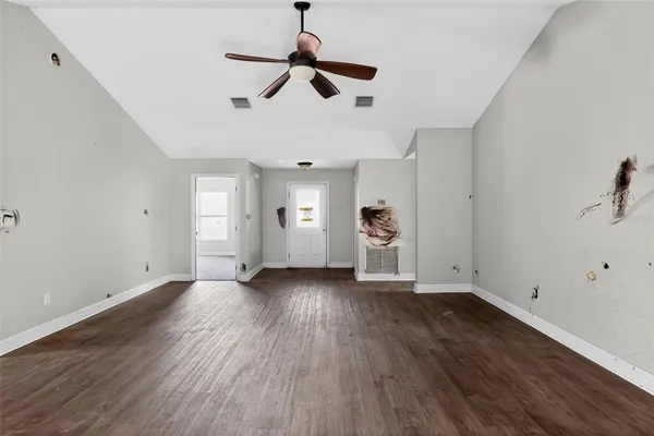 an empty room with wooden floor ceiling fan and windows