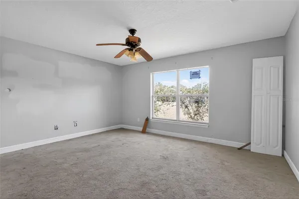 an empty room with windows and a ceiling fan