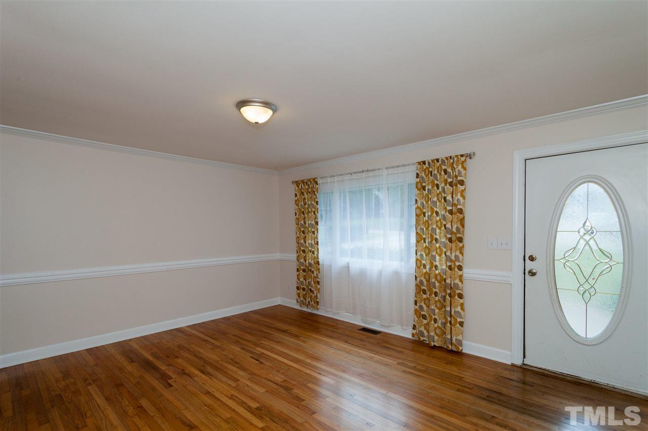 2313 Sheffield Road Raleigh, NC 27610 - Photo 6 of 25 an empty room with wooden floor mirror and windows