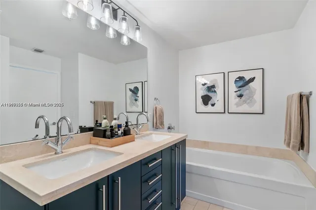 a bathroom with a sink a large mirror and a bathtub