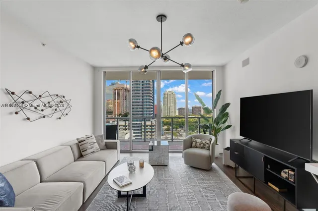 a living room with furniture a chandelier and a flat screen tv