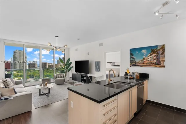 a kitchen with a stove a sink and a flat screen tv