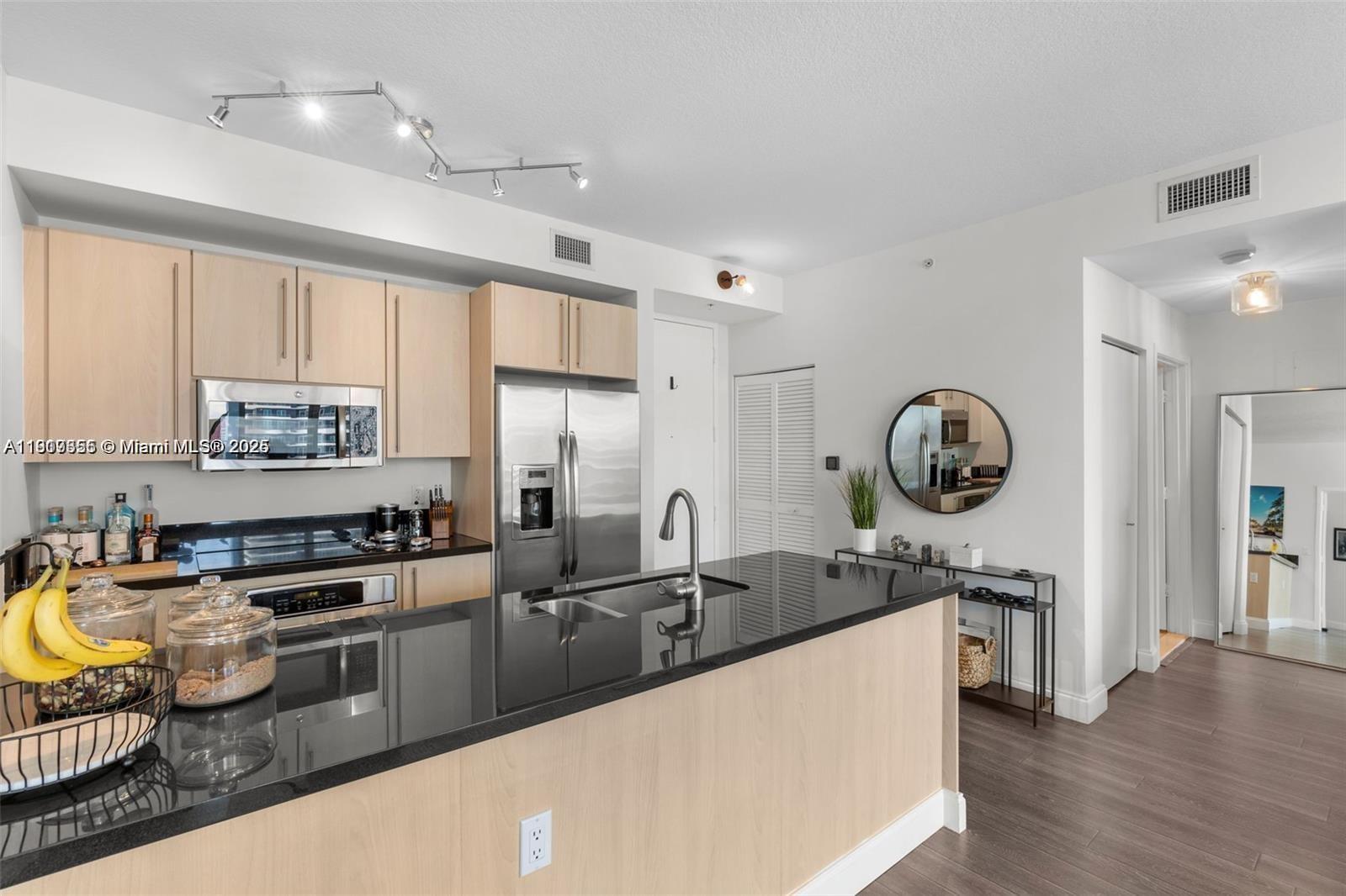 79 Southwest 12th Street, Unit 2204S Miami, FL 33130 - Photo 8 of 27 a kitchen with stainless steel appliances granite countertop a sink a stove and a wooden floors