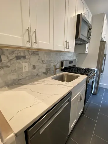 a kitchen with granite countertop a sink a stove and cabinets