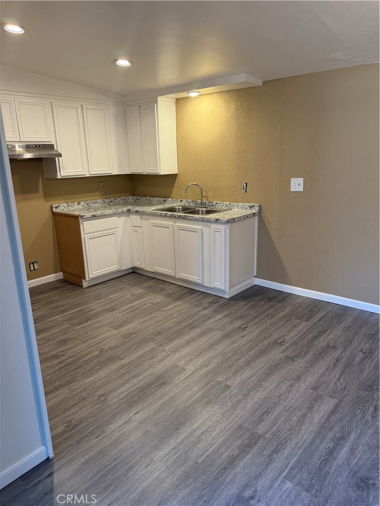 6030 Ocotillo Avenue Twentynine Palms, CA 92277 - Photo 2 of 10 a large white kitchen with wooden floors and white stainless steel appliances