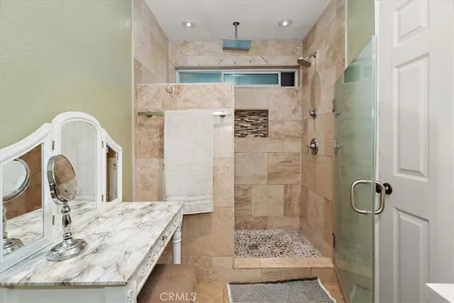 a bathroom with a granite countertop sink a mirror and shower