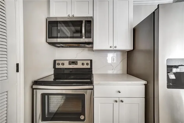 a kitchen with stainless steel appliances granite countertop white cabinets a stove top oven and dishwasher