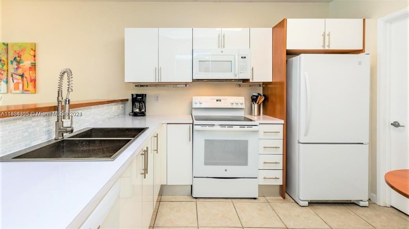 18100 North Bay Road, Unit 606 Sunny Isles Beach, FL 33160 - Photo 10 of 30 a kitchen with granite countertop a sink a refrigerator a stove and white cabinets