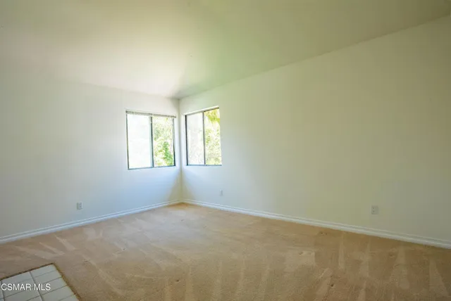 an empty room with a fireplace and windows