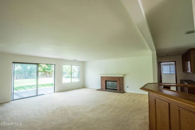 a view of an empty room with window and fire place