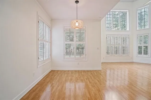 a view of an empty room with wooden floor and windows