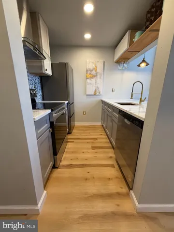 a kitchen with granite countertop a sink a counter top space stainless steel appliances and cabinets