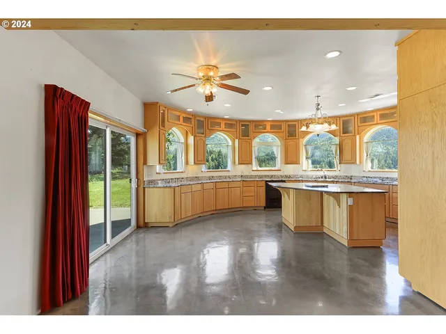 a view of a kitchen with kitchen island granite countertop a sink and a large window