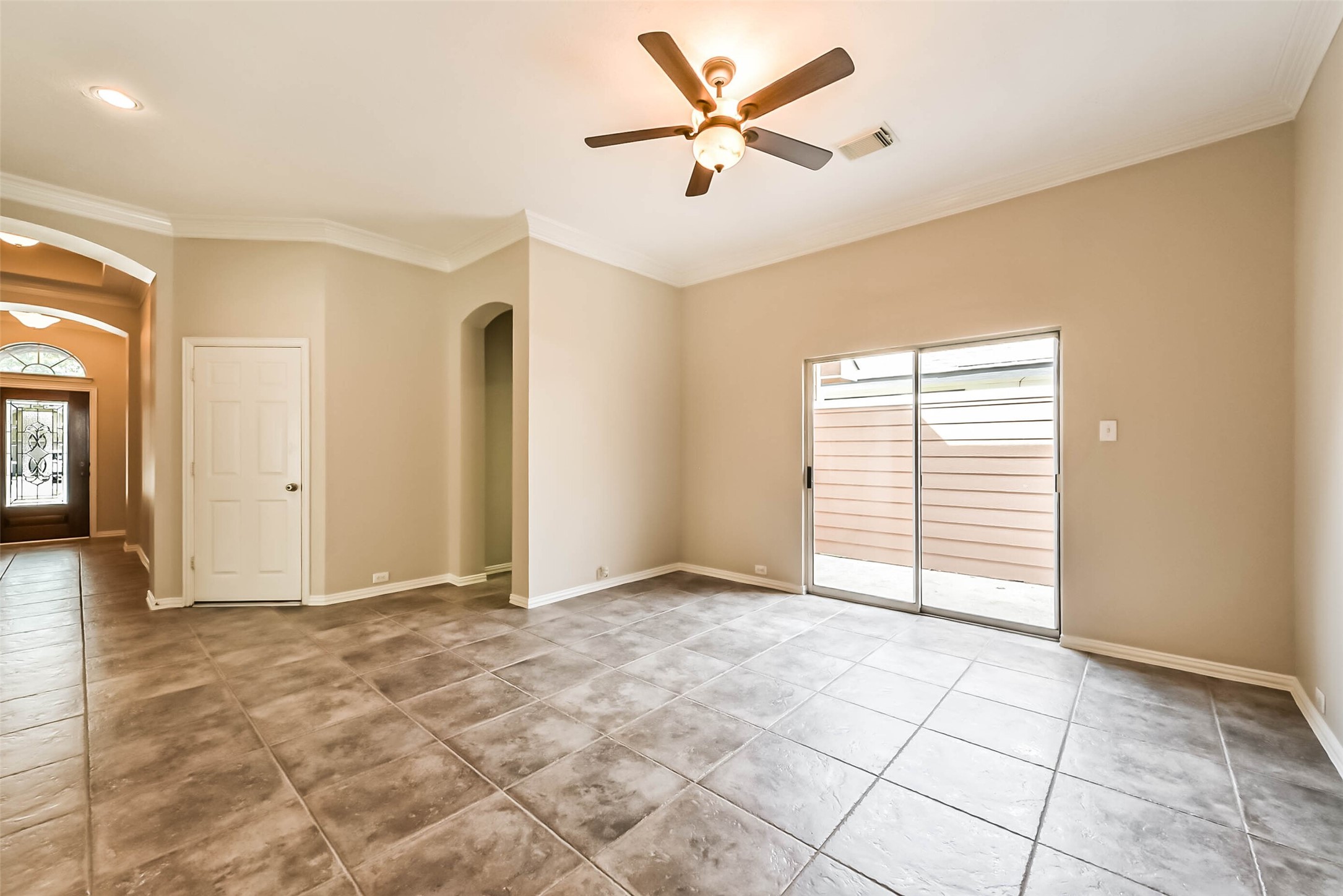 30910 Blue Ridge Park Lane Spring, TX 77386 - Photo 17 of 50 Spacious living area with large tile flooring, neutral walls, and a ceiling fan, leading to a bright sliding glass door that opens to the outdoor space.