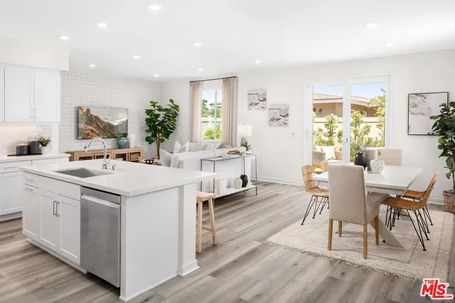 a kitchen with a dining table chairs and wooden floor