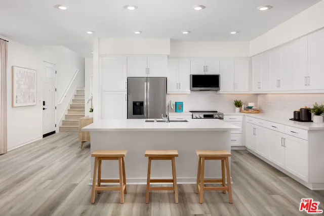 a kitchen with stainless steel appliances granite countertop a stove a sink a microwave a refrigerator and white cabinets