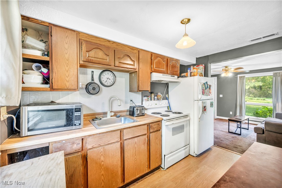 4032 Hanford Road Wakeman, OH 44889 - Photo 37 of 50 Kitchen featuring ceiling fan, pendant lighting, sink, white appliances, and light hardwood / wood-style flooring